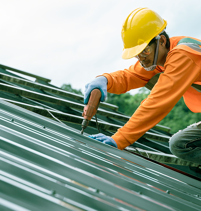 Homem com equipamentos de segurança realizando a instalação de telhas 